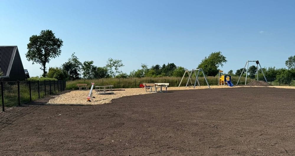 Weite Ansicht des Spielplatzes am Langbarg mit Spielgeräten und Freifläche.